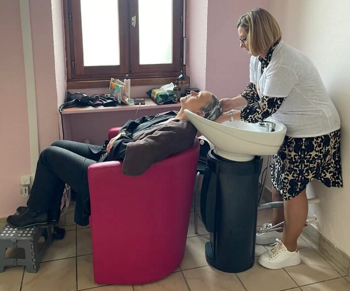 Atelier coiffure, une fasse se fait faire un shampoing.