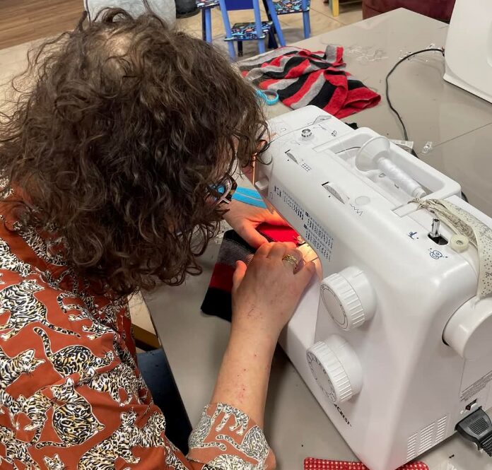 Atelier couture, une femme fait de la couture avec une machine à coudre.