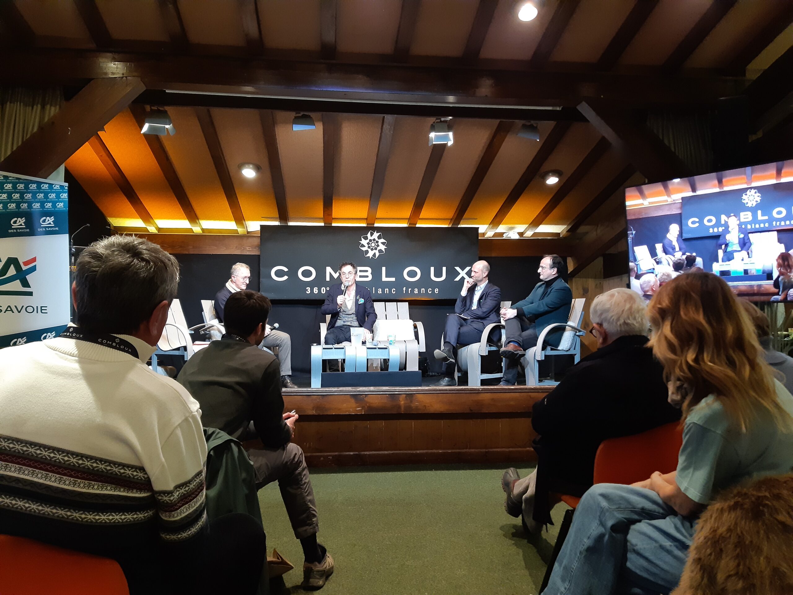 Public de dos, avec la scène en fond. Sur la scène des échanges entre plusieurs personnes.