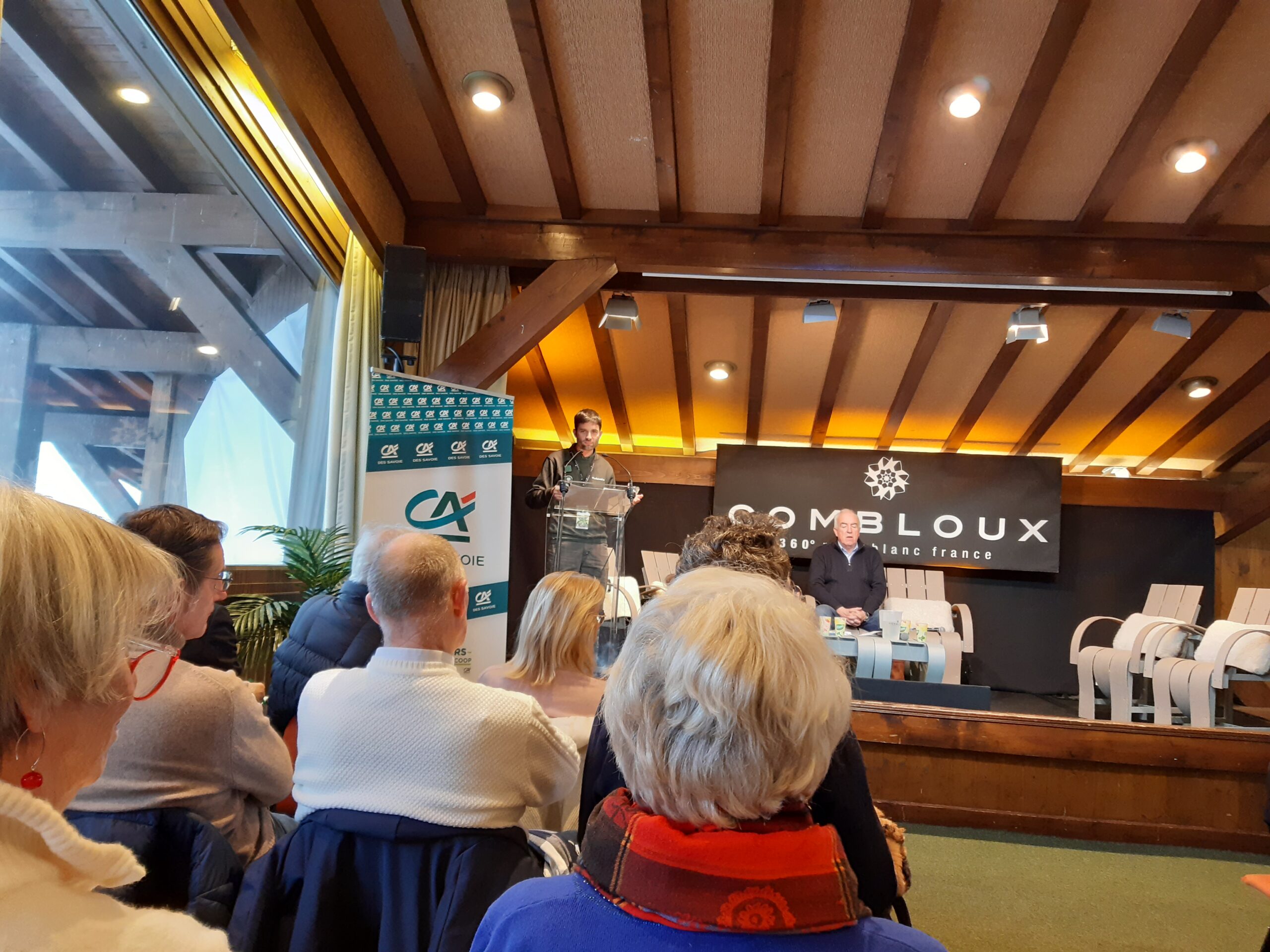 Public de dos, avec la scène en fond. Sur la scène des échanges entre plusieurs personnes.