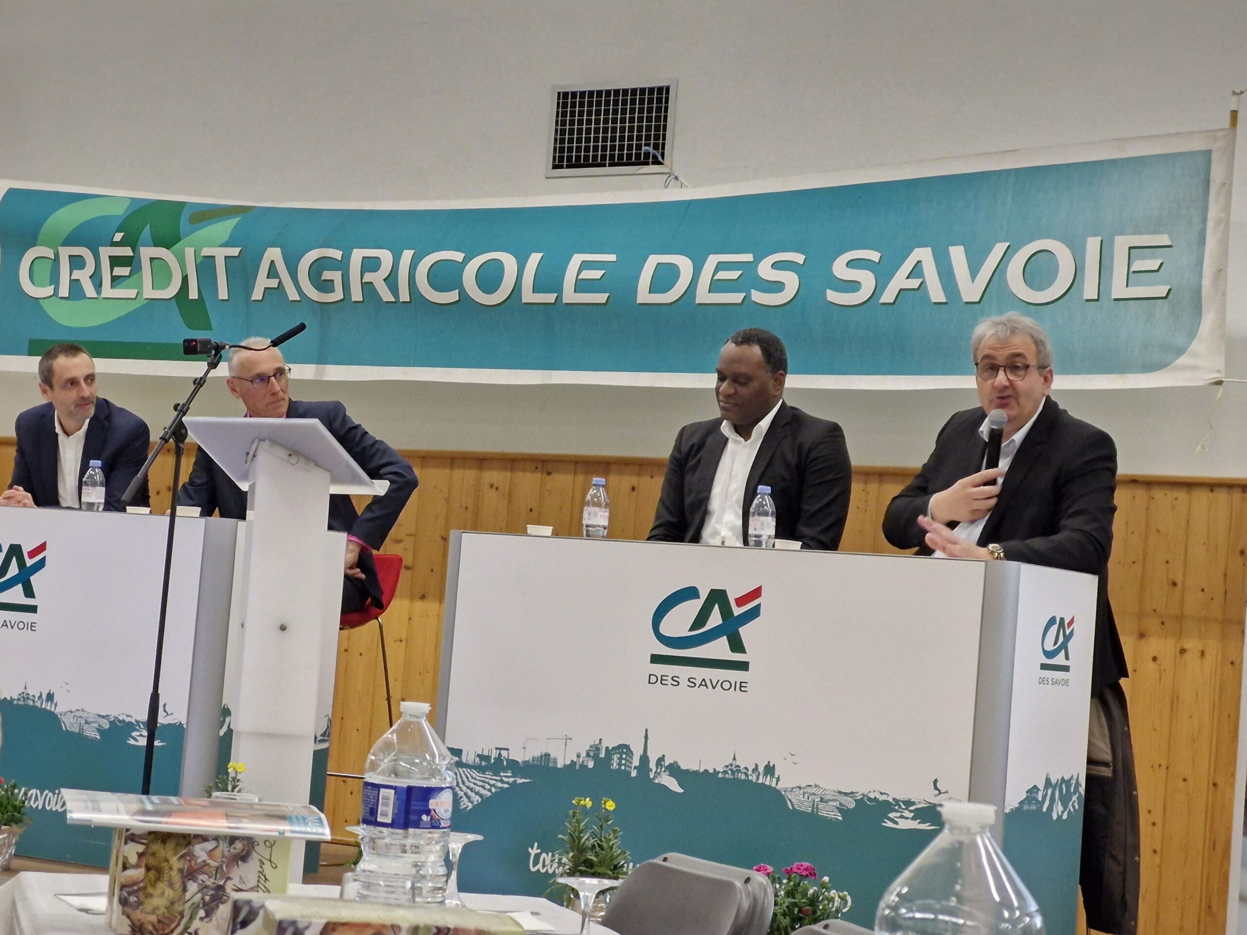 Sur scène, derrière des bureaux, 4 représentants du Crédit Agricole des Savoie.