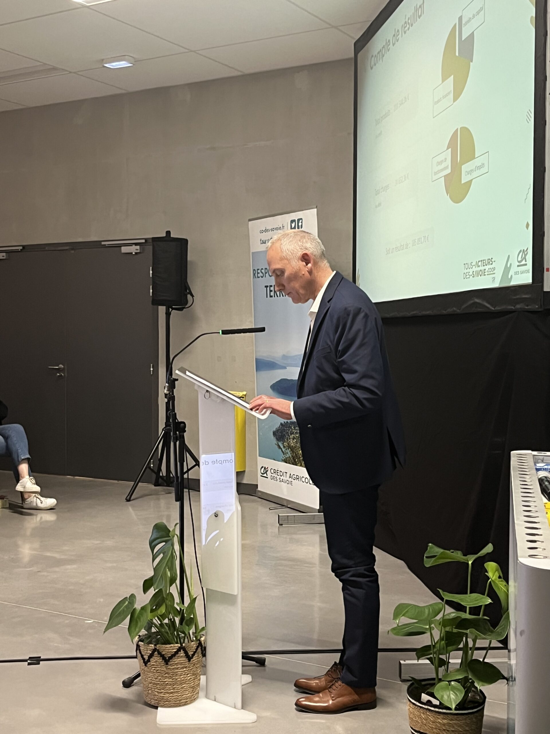 Sur scène, une personne faisant un discours au pupitre.