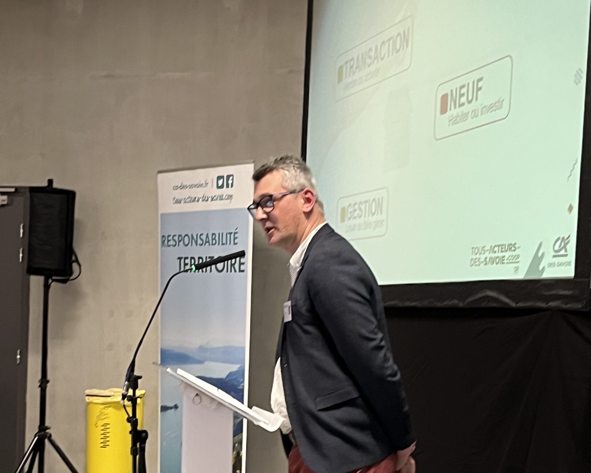 Sur scène, une personne faisant un discours au pupitre.