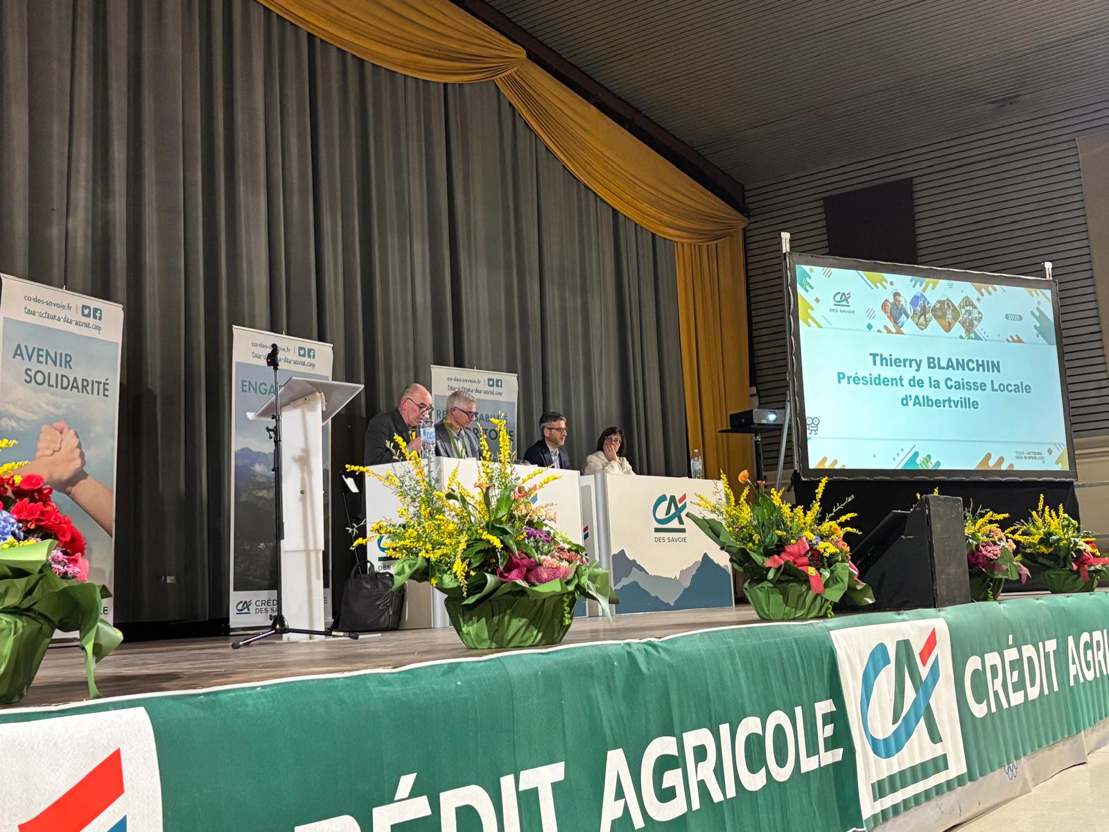 Sur scène, 4 personnes à un bureau.