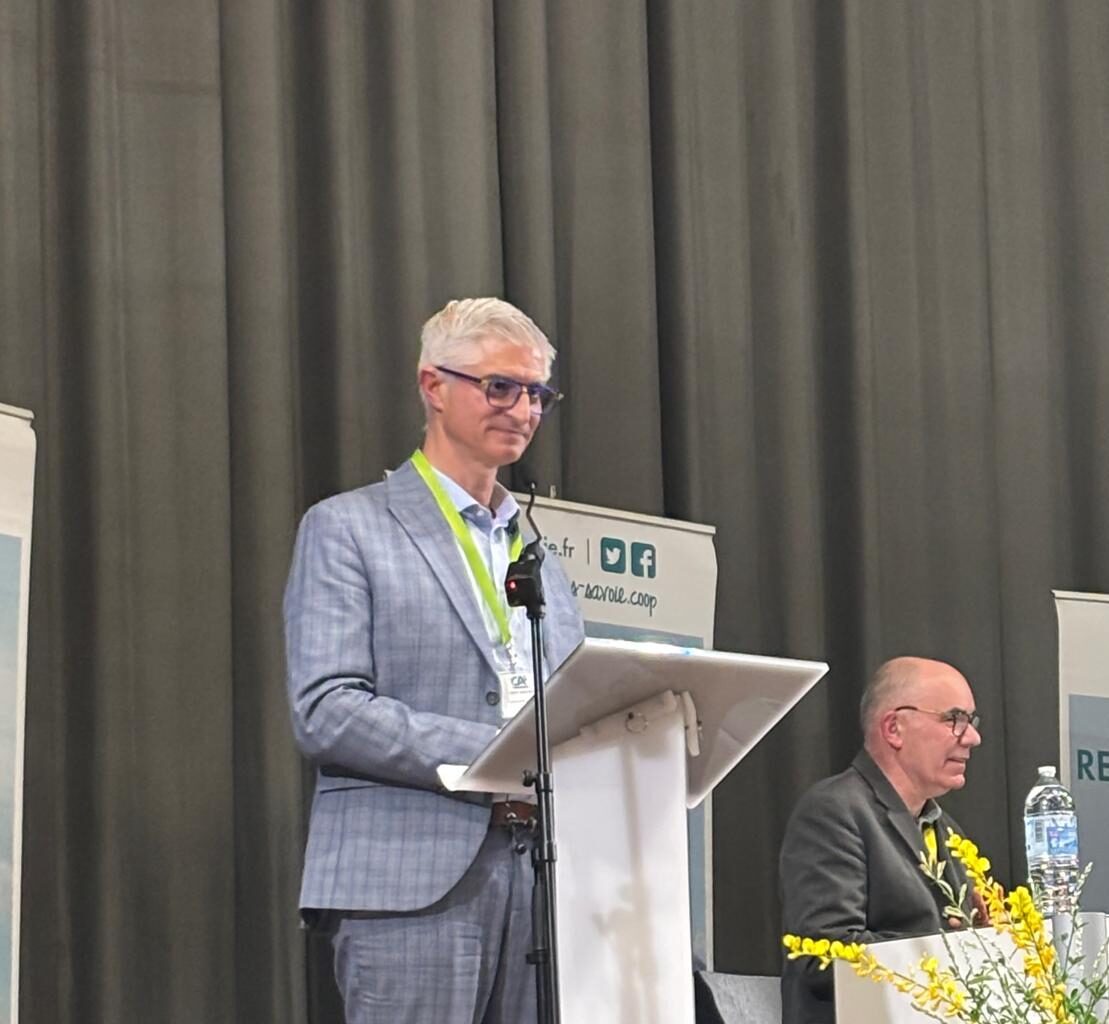 Sur scène, une personne faisant un discours à un pupitre.