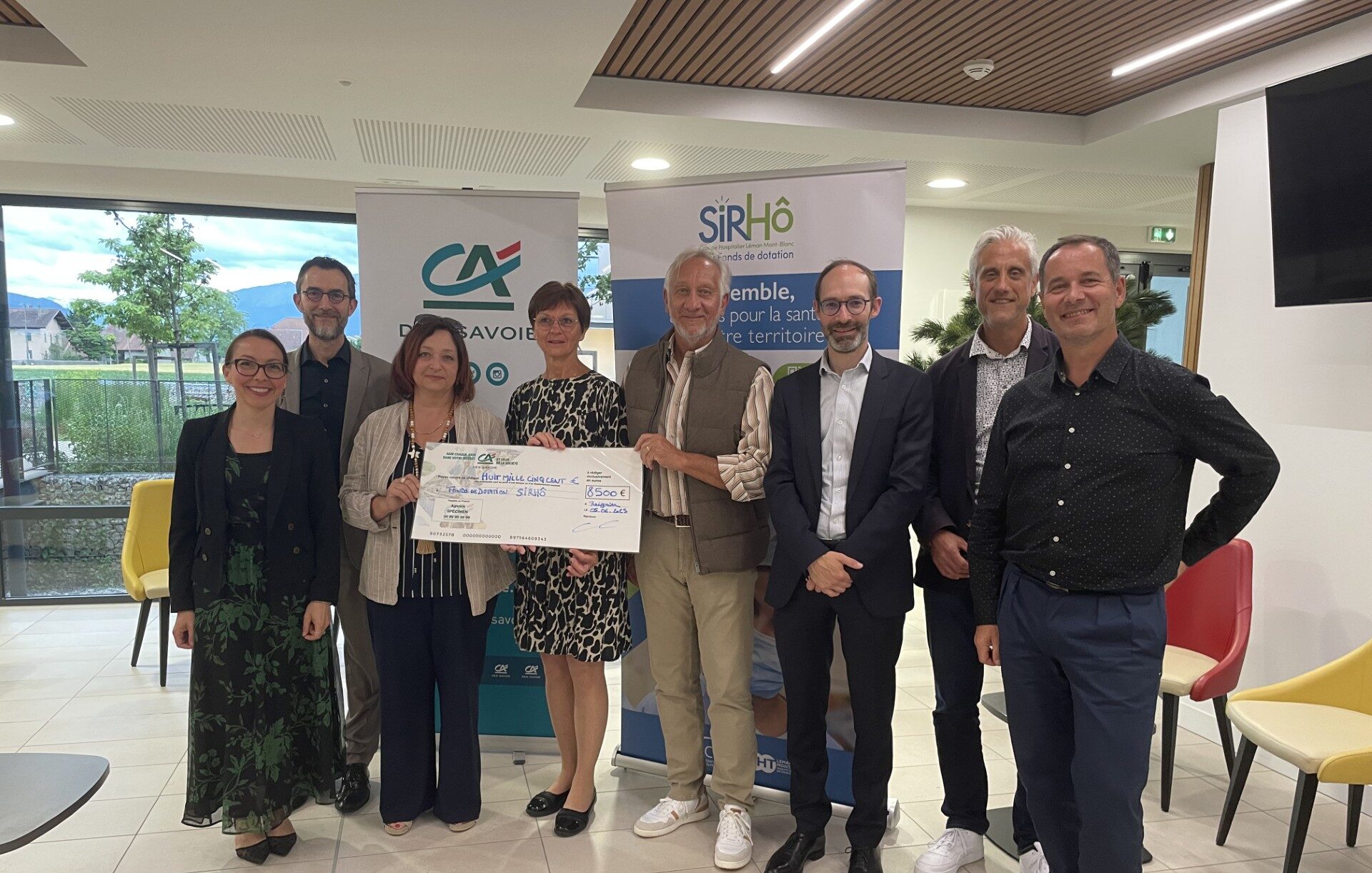 La photo montre un chèque de donation de huit mille cinq cents euros (8500€) remis par le Crédit Agricole des Savoie au nom de la Fondation Crédit Agricole Solidarité et Développement à l'EPSM 74 (Établissement Public de Santé Mentale de Savoie). 8 personnes sont présentes sur la photo, devant le kakémono Crédit Agricole des Savoie et le kakémono SIRHÔ, elles tiennent le chèque de dotation.