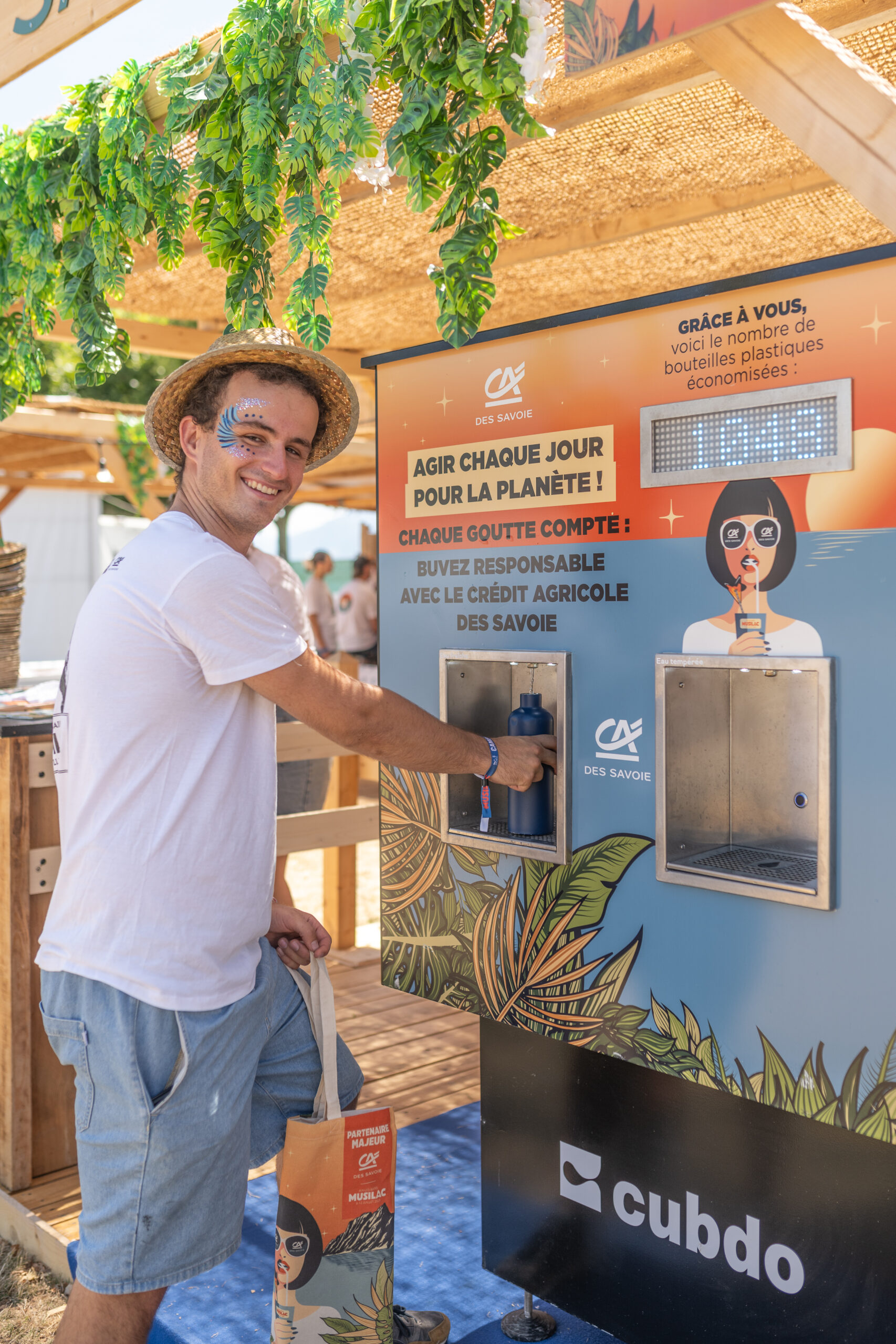 Festivalier qui remplit sa gourde à la fontaine à eau du stand.